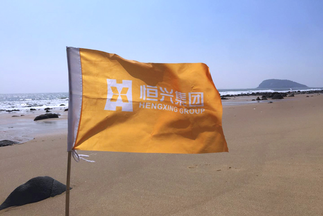 集团旗帜插在火山岛沙滩上.jpg